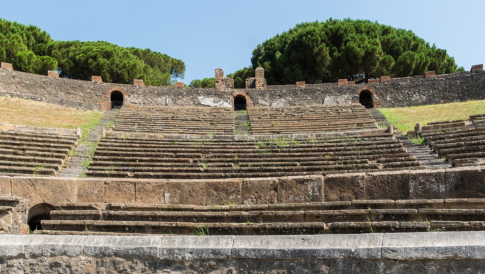 The stone seating of the amphitheatre at Pompeii, with arched openings in the outer wall.